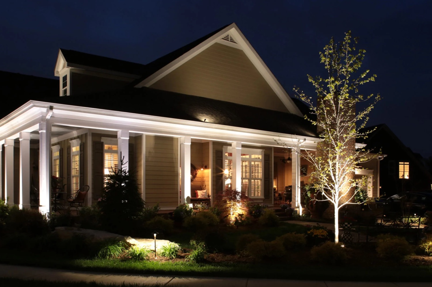 outdoor-lighting-maintenance-service-calls Delta Outdoor Lighting soffit and tree uplighting on a wraparound porch farmhouse