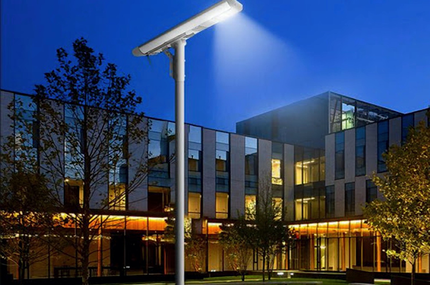 solar-outdoor-lighting-installation Solar-powered LED street light fixture mounted outside a commercial glass building